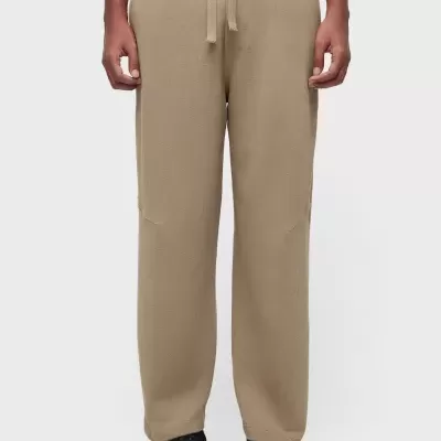 Calças castanhas com cordão, usadas com ténis e camiseta preta