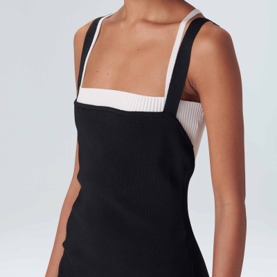 Mulher a usar top branco de malha canelada com vestido preto de alças largas