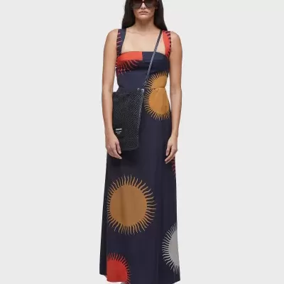 Modelo com vestido azul-marinho com padrão de círculos solares coloridos e saco preto
