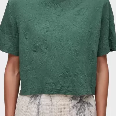 Camiseta cropped verde com textura amarrotada e calças brancas com padrão cinzento