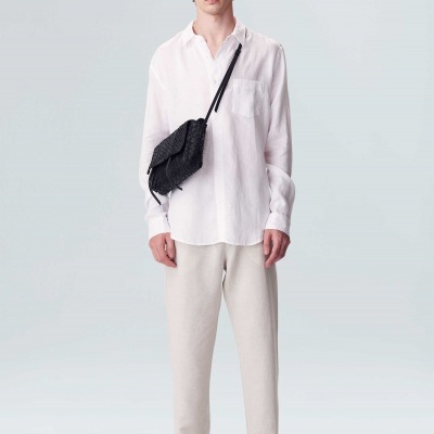 Homem com camisa branca, calças bege, sandálias pretas e mochila preta