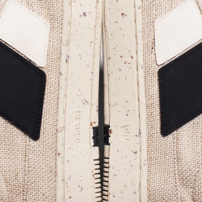 Fecho éclair branco com pontos castanhos em tecido bege com detalhes em preto e branco.