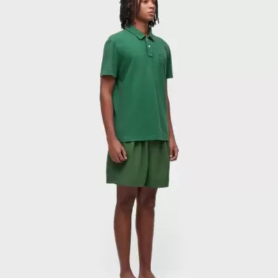 Homem com polo verde, calções verdes e chinelos brancos