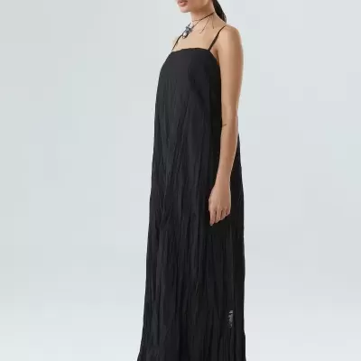 Vestido longo preto com alças finas usado por mulher em fundo branco