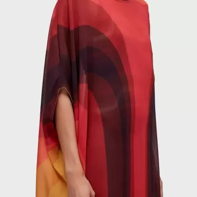 Vestido colorido com padrão geométrico e corte largo em fundo cinza.