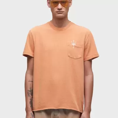 Camiseta laranja claro com bolso e detalhe em branco no peito, modelo com calções laranja e óculos amarelos