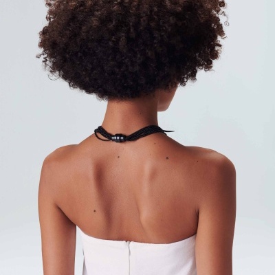 Mulher vista de costas usando colar preto de múltiplas cordas com fecho prateado