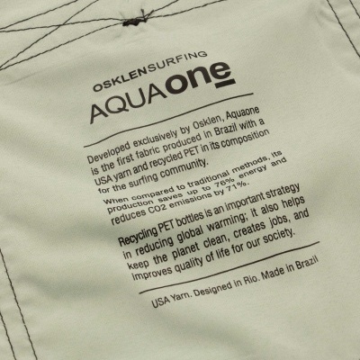 Tecido bege com texto impresso 'OSKLENSURFING AQUAone' e informações sobre o tecido sustentável.