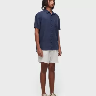 Homem a usar camisa azul escura, calções brancos e ténis bege