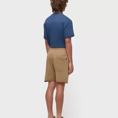 Homem de costas com t-shirt azul e calções castanhos