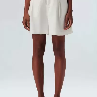 Calções brancos de tecido liso com fecho e bolsos usados por modelo