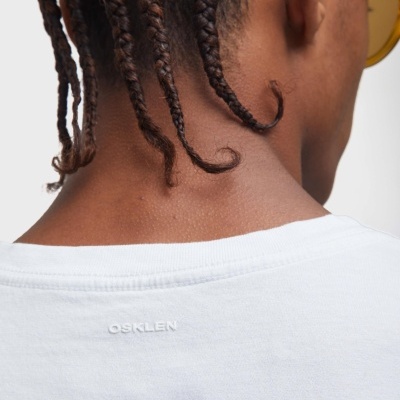 Pessoa vista de costas com t-shirt branca com texto OSKLEN bordado.