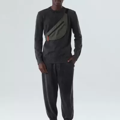 Homem com roupa desportiva preta e pochete verde oliva, fundo branco