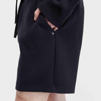 Calções pretos com bolso lateral usados por uma pessoa com camisola preta de malha