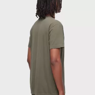 Pessoa de costas com t-shirt verde-oliva e calças verdes.