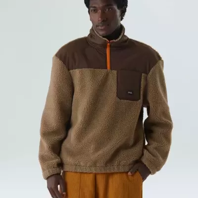 Camisola sherpa castanha com bolso e fecho laranja usada por modelo