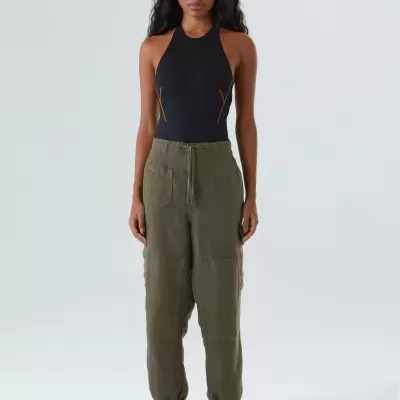 Mulher veste blusa preta justa com alças e calças cargo verdes com bolsos e cordão na cintura