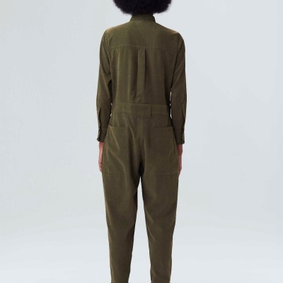 Macacão verde-oliva visto de costas com botas brancas e pretas