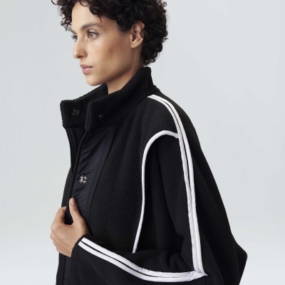 Casaco preto texturizado com detalhes brancos nas mangas e ombros, gola alta, modelo de perfil