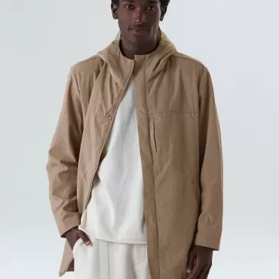 Homem com casaco bege claro com capuz e camisola branca