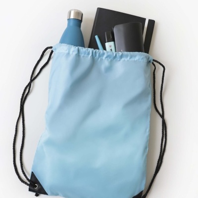 Mochila saco azul claro com garrafa metálica azul, caderno preto e canetas