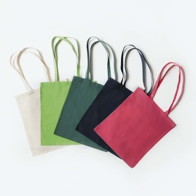 Cinco sacos de algodão em várias cores alinhados sobre superfície branca