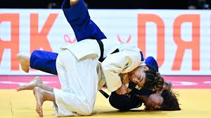 Dois praticantes de judo em kimono branco e azul a lutar num tatami amarelo