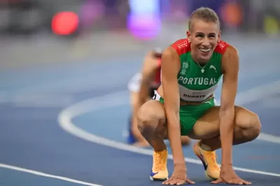 Atleta masculino a agachar-se na pista de atletismo com fato verde Portugal