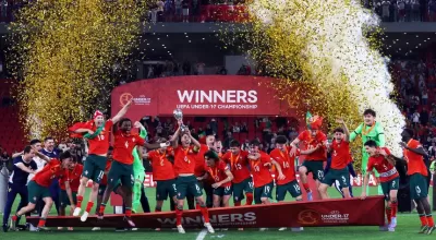 Jogadores juvenis de futebol comemoram com troféu e medalhas num palco vermelho com texto WINNERS UEFA UNDER 17 CHAMPIONSHIP