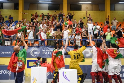 Jogadores de patinagem com bandeira de Portugal a aplaudir público num pavilhão desportivo