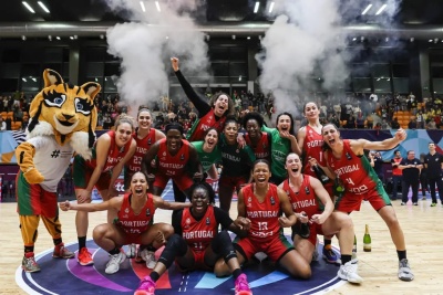 Equipa feminina de basquetebol de Portugal posando em campo com mascote e fumaça no estádio