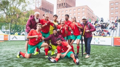 Grupode jogadores de futebol em campo relvado com camisolas vermelhas e calções verdes