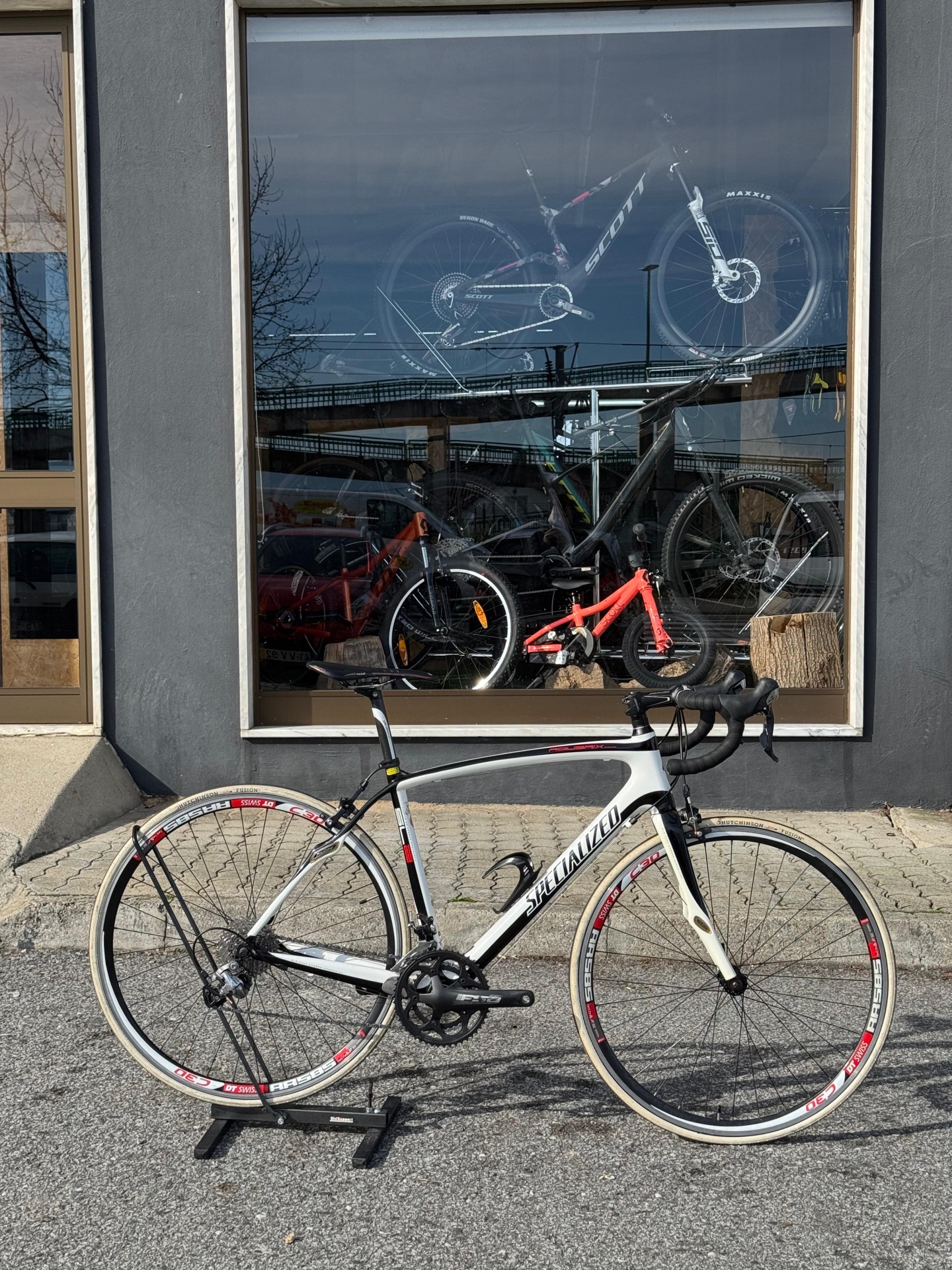 Bicicleta de estrada Specialized branca com detalhes pretos e vermelhos junto a montra