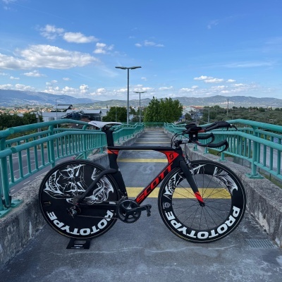 Bicicleta de estrada preta e vermelha Scott com rodas ROTOTYPE num passeio com guarda-corpos verdes