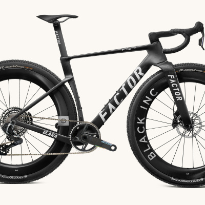 Bicicleta de estrada preta com grandes pneus de cravo e quadro em carbono.