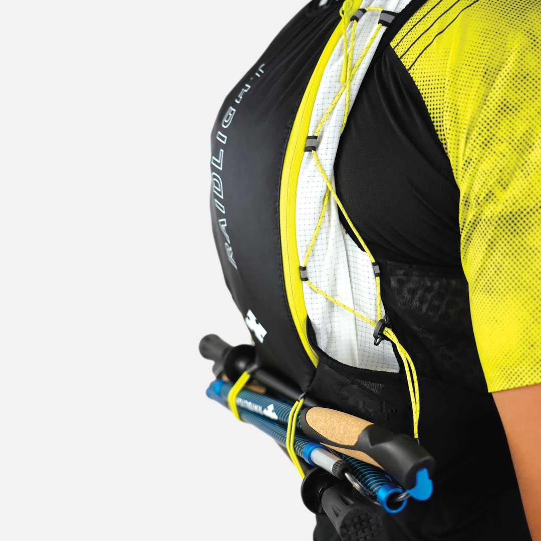 Colete desportivo preto, branco e amarelo com bastões de caminhada azuis