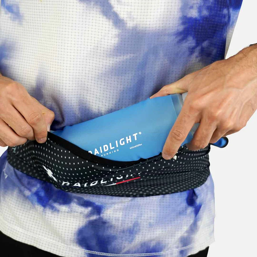 Pessoa a guardar uma garrafa azul RAIDLIGHT numa sacola de desporto preta com padrão de pontos brancos.