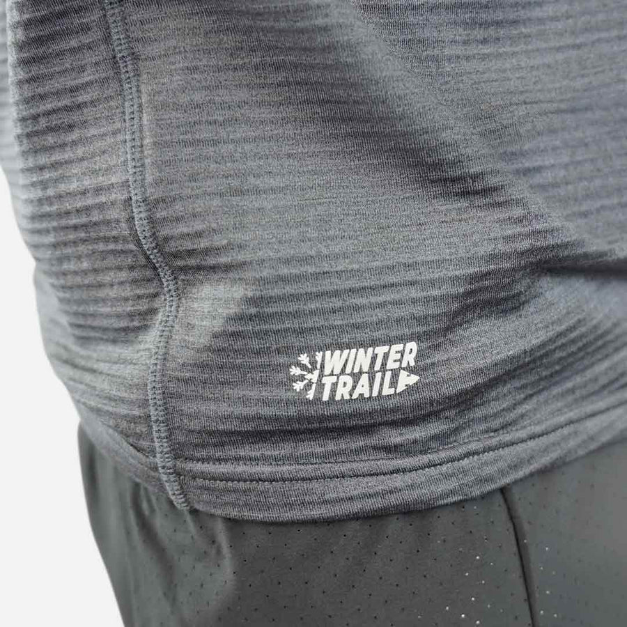 Peça de roupa desportiva cinzenta com logótipo WINTER TRAIL e calças pretas com pontos pequenos