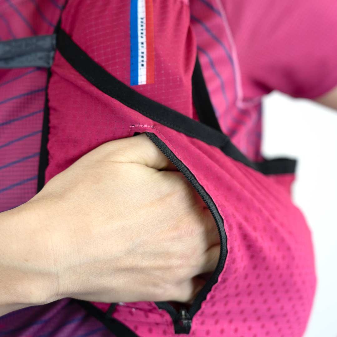 Bolsa rosa com padrão perfurado e bordas pretas, com logo colorido e mão dentro