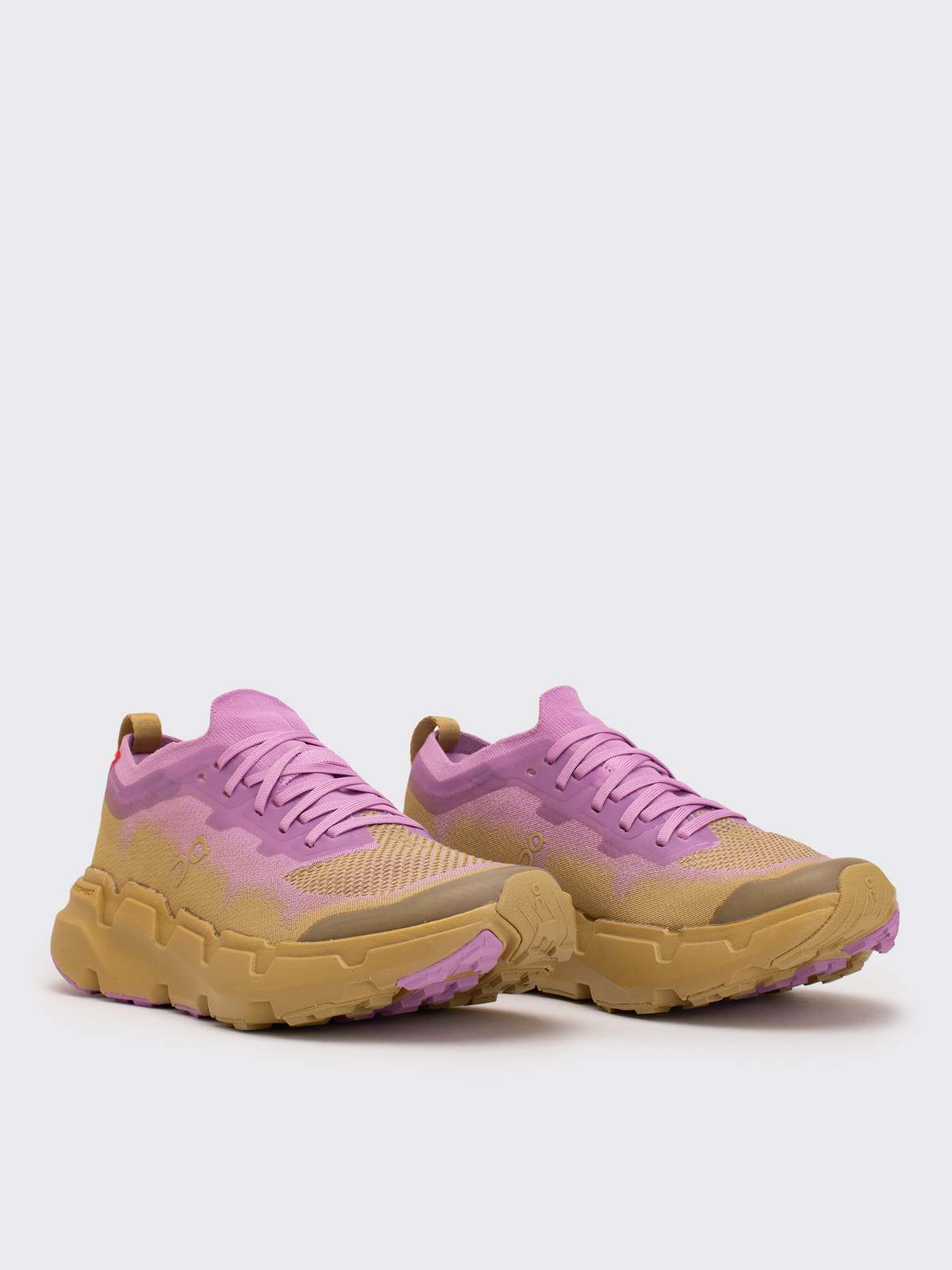 Ténis desportivos rosa e bege com sola castanha sobre fundo branco