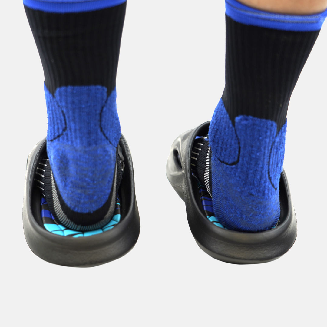 Sandálias pretas com sola azul usadas com meias pretas com detalhes azuis