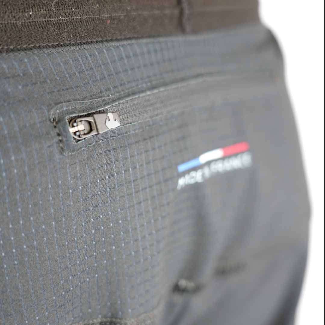 Pormenor de roupa cinzenta com fecho e logótipo colorido