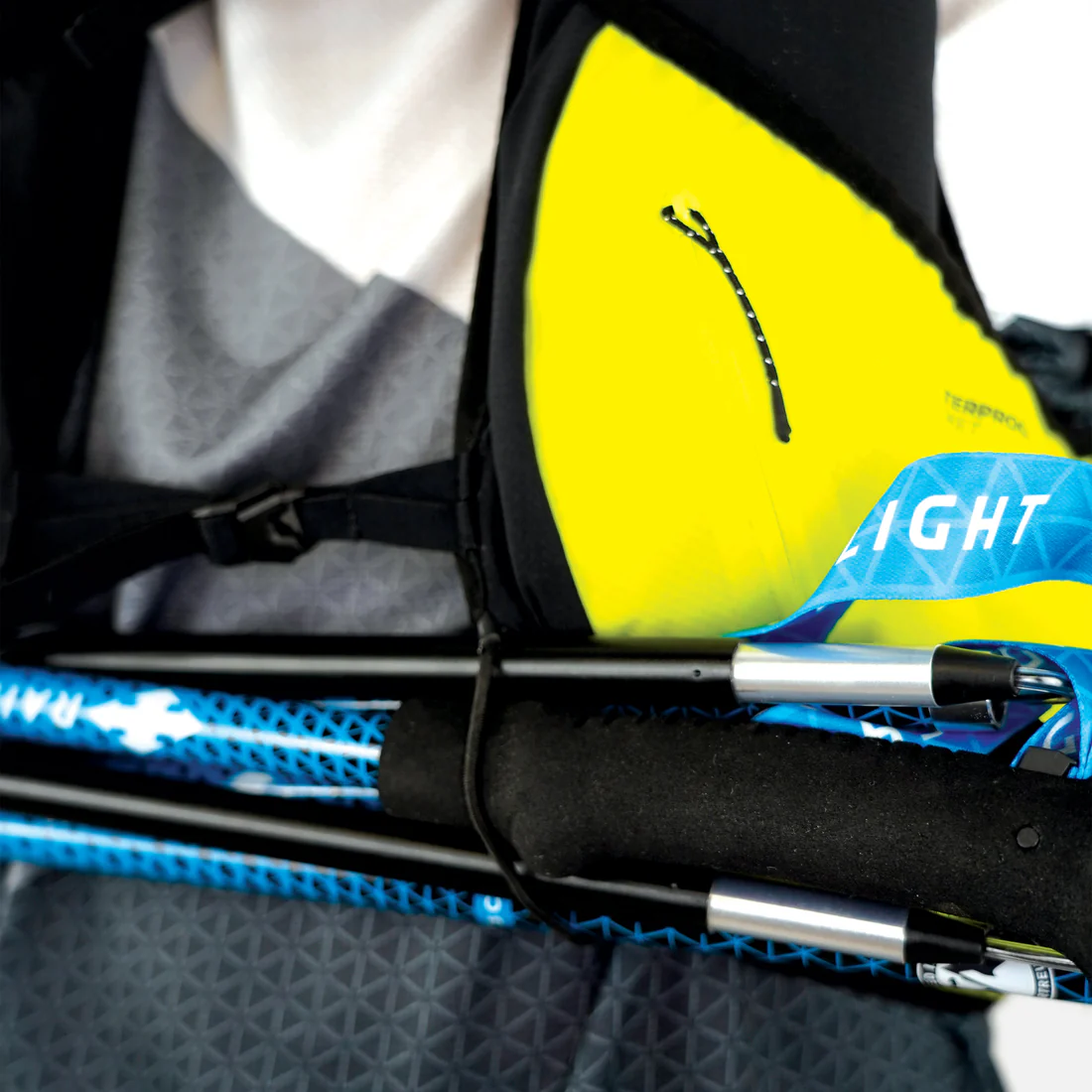 Saco mochila preta amarela com texto TERROX 17 e bastões de caminhada azuis com fita azul LIGHT