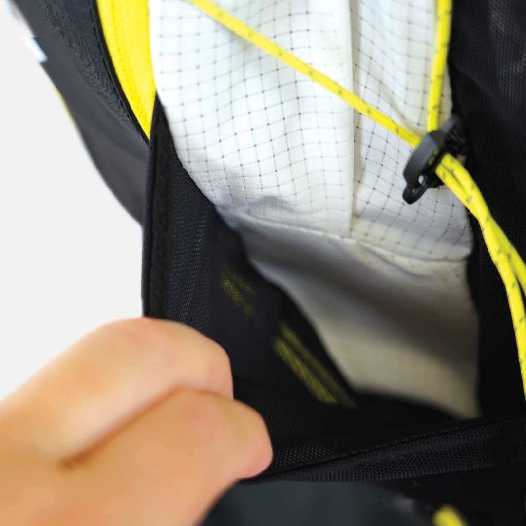 Interior de mochila preta com detalhes amarelos e tecido branco riscado com quadrícula