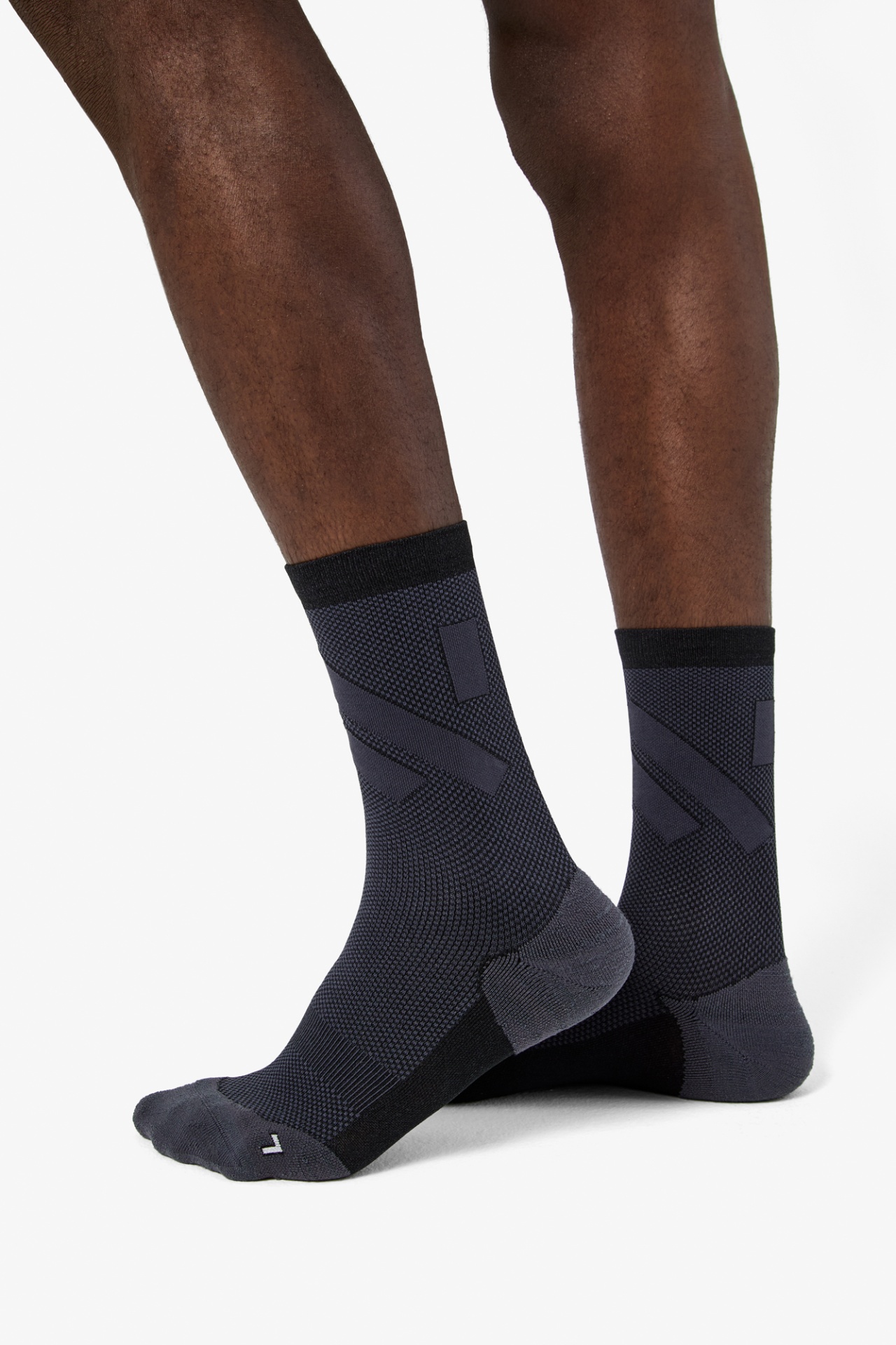 Meias desportivas em cinza escuro e preto em pernas masculinas.