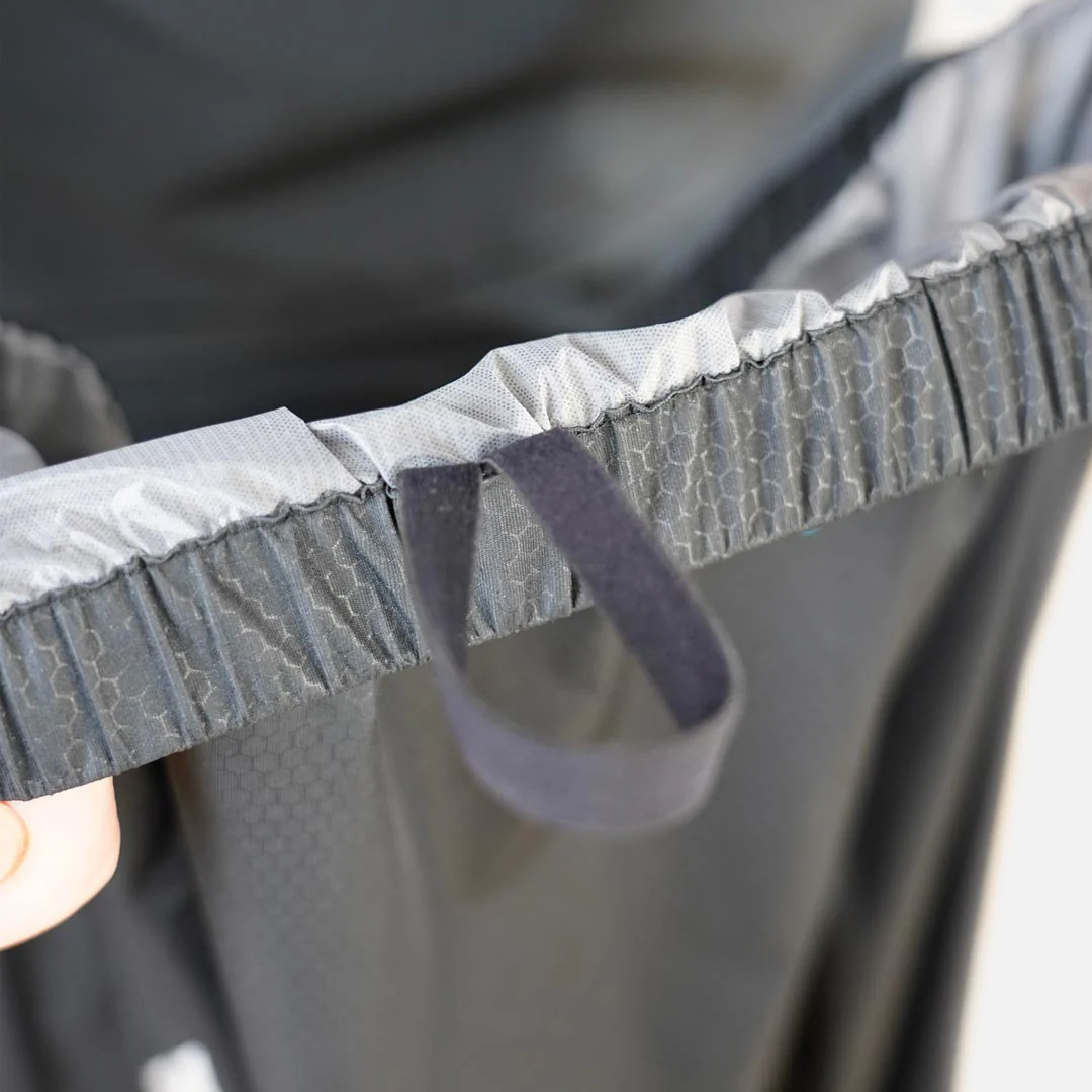 Detalhe de tecido preto com padrão hexagonal e faixa elástica cinza com alça preta.