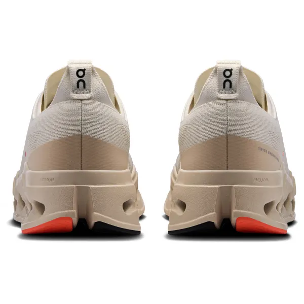 Ténis bege claro com sola robusta bege e detalhes vermelhos e pretos vistos de trás