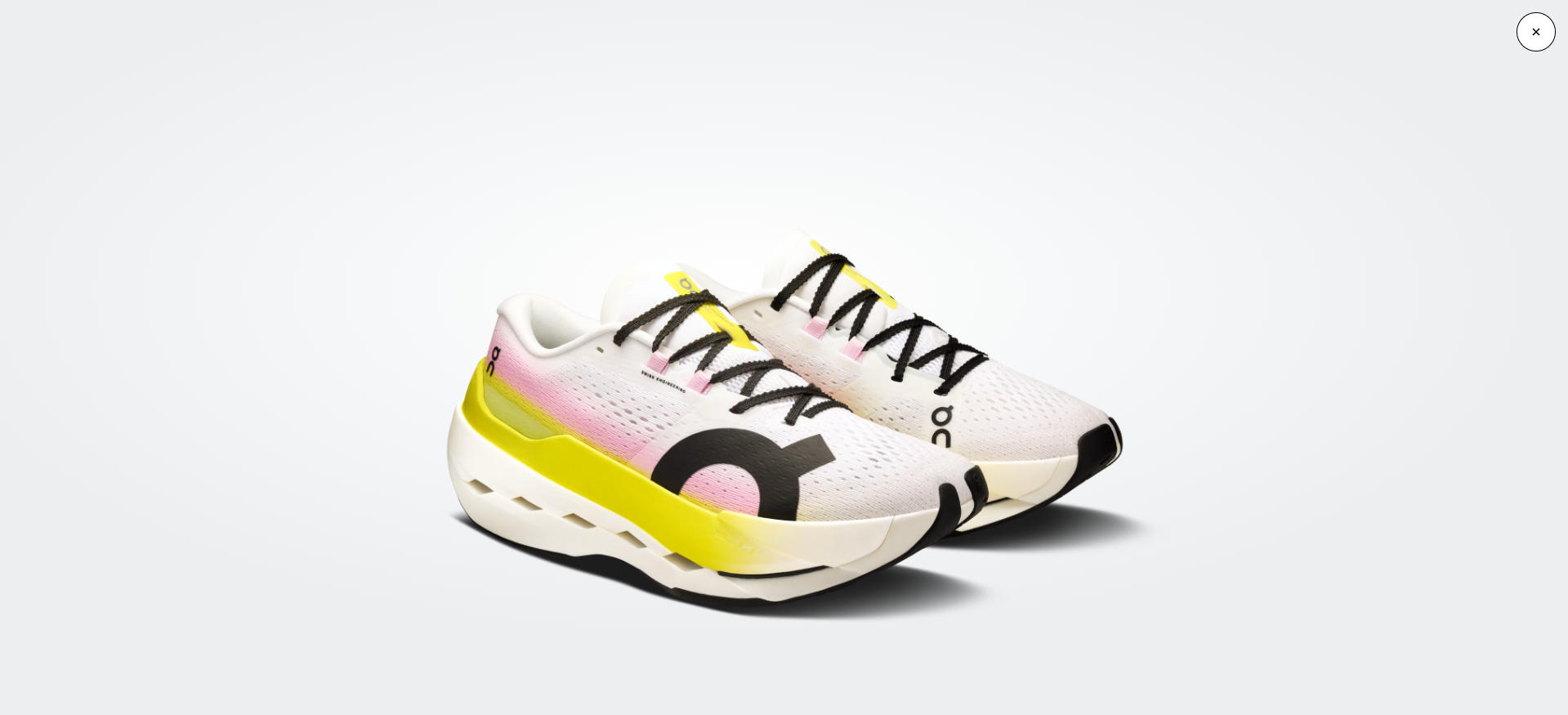 Ténis desportivos brancos com detalhes amarelos e rosa e sola branca e preta.