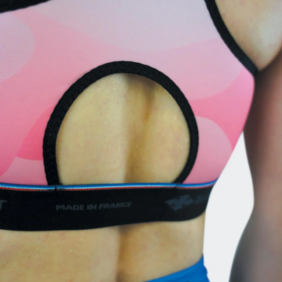 Top desportivo rosa com abertura circular e faixa preta com texto