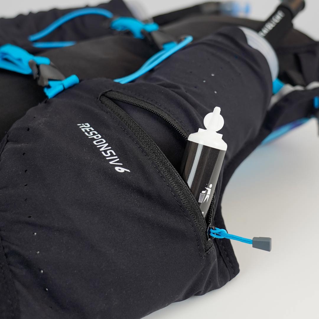 Mochila preta com fecho azul e etiqueta RESPONSIV 6 com tubo branco no bolso aberto